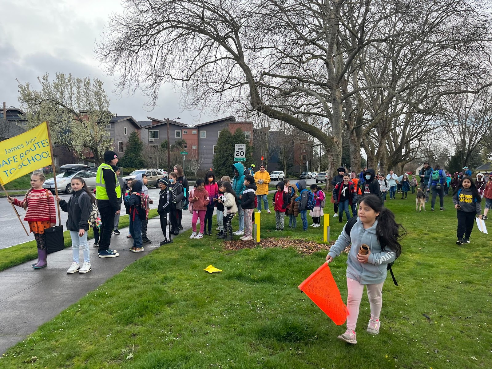 James John students holding plants and signs outdoors as they prepare to walk to school on Walk and Roll Day.